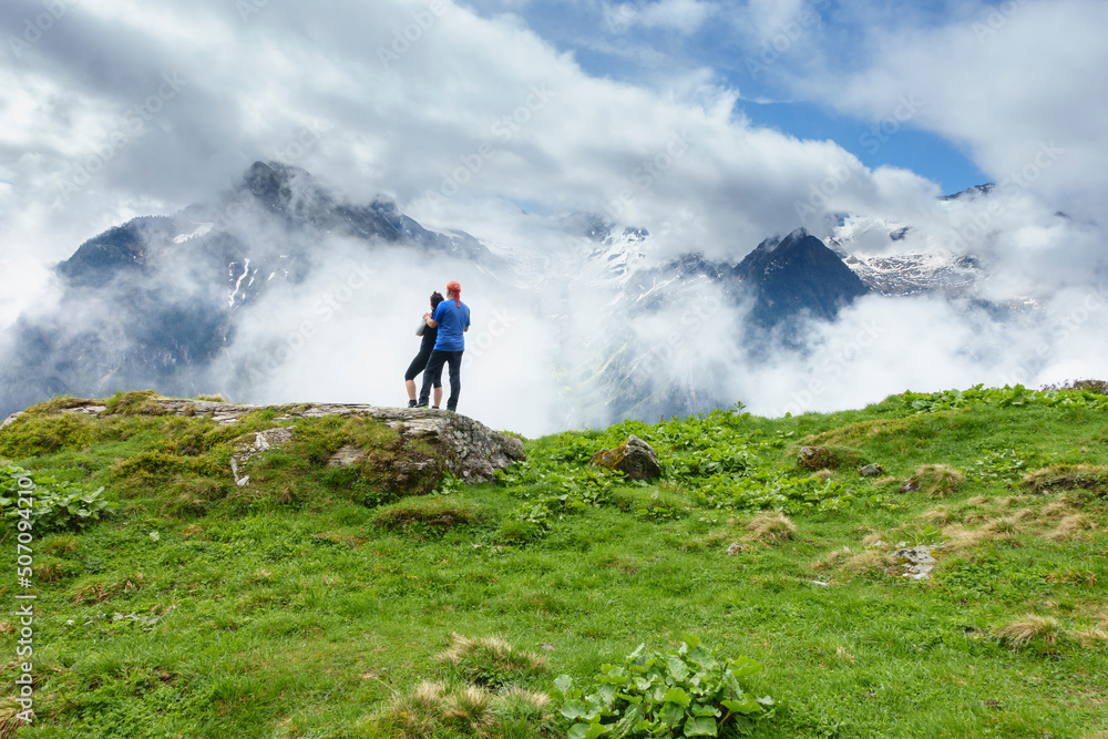zwei Wanderer blicken in eine wolkenverhangene Bergwelt