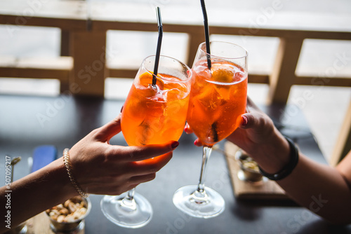 Aperol. Two glasses of aperol. People are holding glasses of aperol.