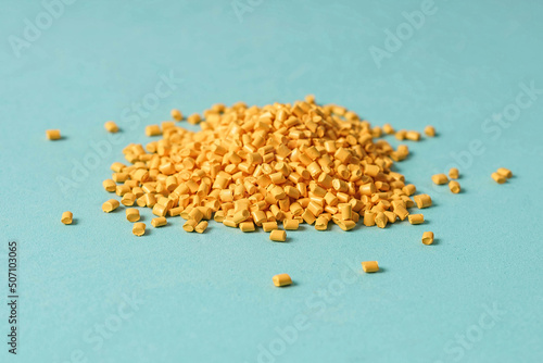 Yellow plastic granules on a blue background, Polymeric dye. photo