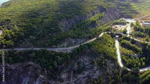Aerial view of a curvy mountain road in sunny Setubal, Portugal - pan, drone shot photo
