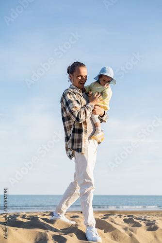 Positive father holding toddler child walking walking on beach in Treviso. © LIGHTFIELD STUDIOS