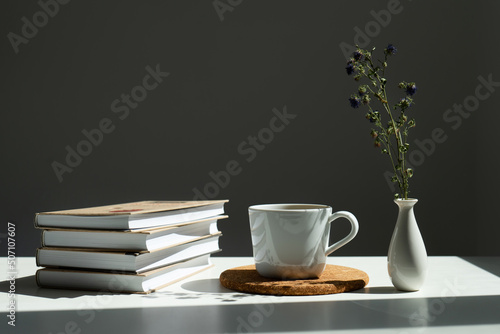 books  a mug of tea and a vase of flowers.