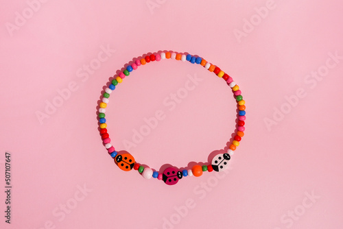 Beautiful handmade beaded bracelet on pink background, top view