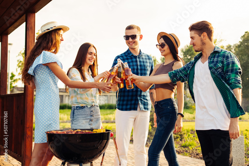 company of friends prepares a barbecue in nature - happy people have fun at a picnic with drinks
