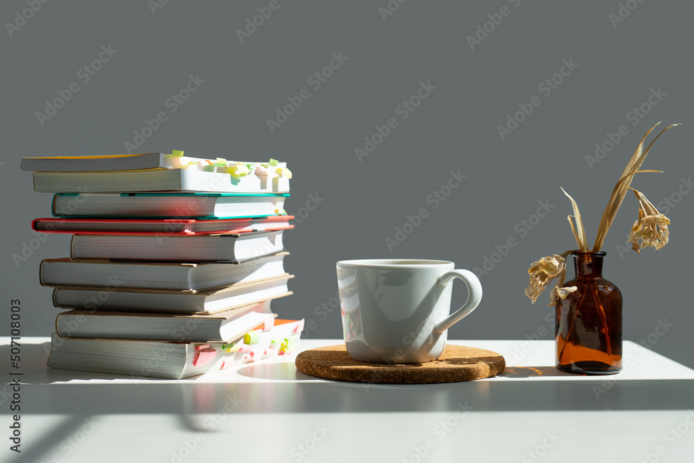 books, a mug of tea and a vase of flowers. books, a mug of tea and a vase of flowers.