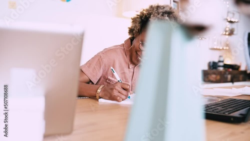 Afro woman writing in a notebook at home on an office table.