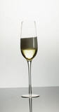 Vertical image of open bottle pouring champagne into single tulip glass on white background