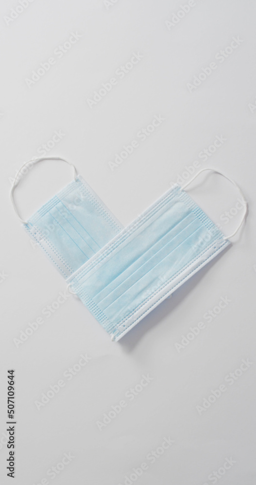 Vertical image of overhead view two face masks forming heart shape on white background Vertical image of overhead view two face masks forming heart shape on white background