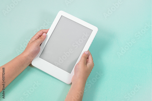 Obraz na plátne Ebook reader over green background - being held by the hand of a child