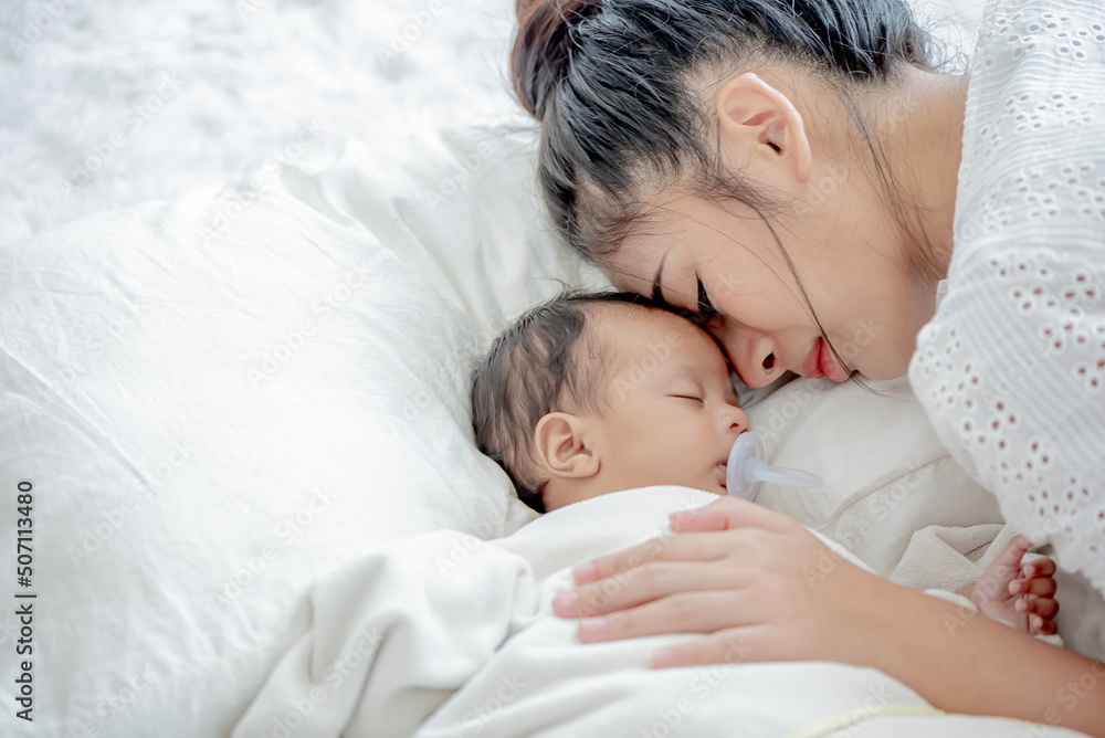 baby and asian mother sleeps and touches her child with tenderness and cherishness baby and asian mother sleeps and touches her child with tenderness and cherishness