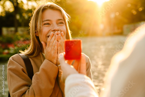 Quadro em tela White man proposing to his excited girlfriend in park