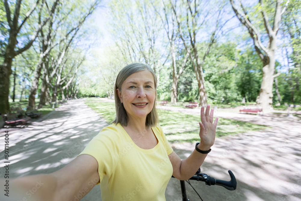Senior active woman in the park talking on a video call, looking at the ...