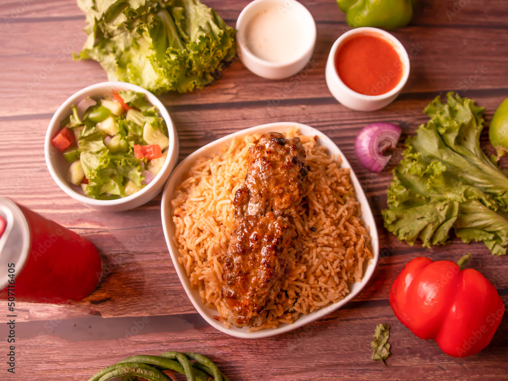 seekh kabab biryani with raita, sauce, salad and drink isolated on wooden background top view of indian and pakistani food seekh kabab biryani with raita, sauce, salad and drink isolated on wooden background top view of indian and pakistani food