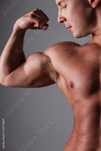 strong handsome sports man bodybuilder with a bare torso and muscles shows a biceps