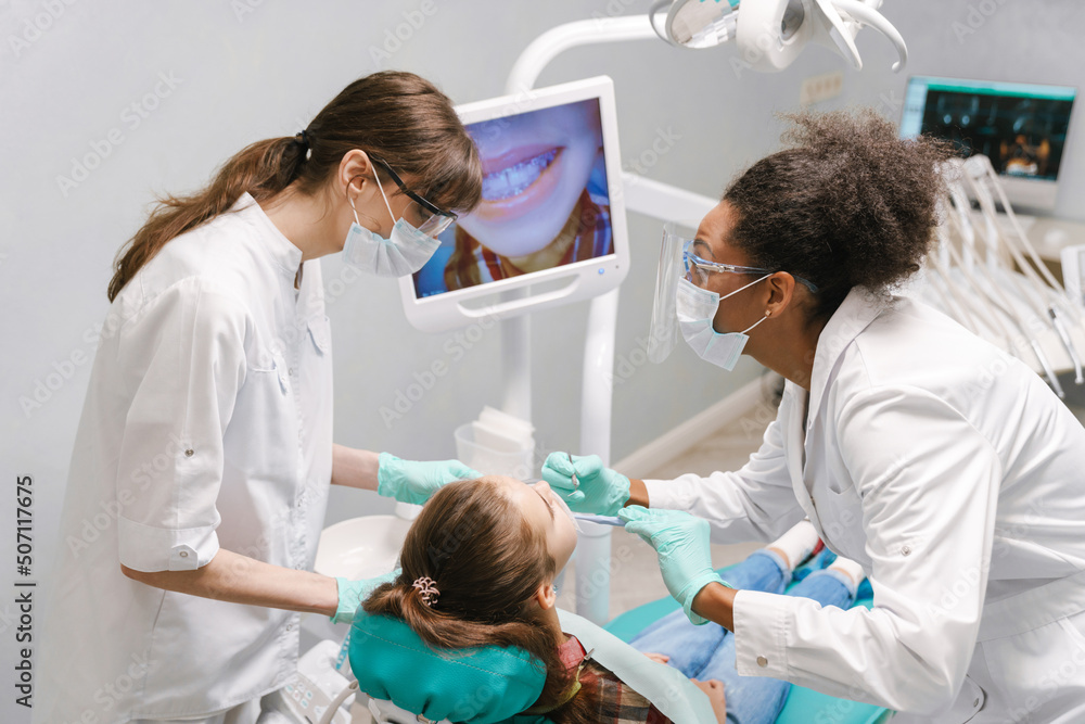 Two multiracial dentists wearing lab coats working in dental clinic