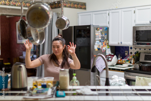 Korean woman in dancing in the kitchen.