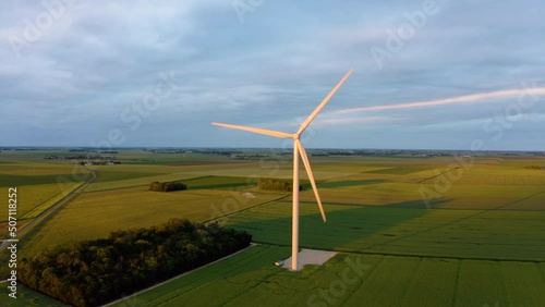 Alternative energy sources with wind mill green energy production. Aerial drone video. windmill park with stormy clouds and a blue sky. Wind turbines on the green lush field. Dark stormy clouds.  photo