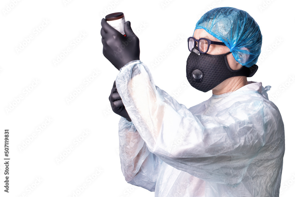 A doctor in medical uniform and wearing respirator and gloves gaining medicine into a syringe for an injection on blue background.