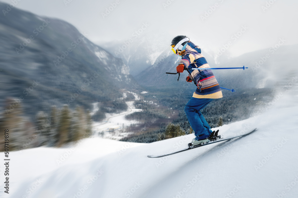 A female athlete skier rides a freeride in a winter forest in the mountains. Jump against the backdrop of snow-covered trees and the setting sun