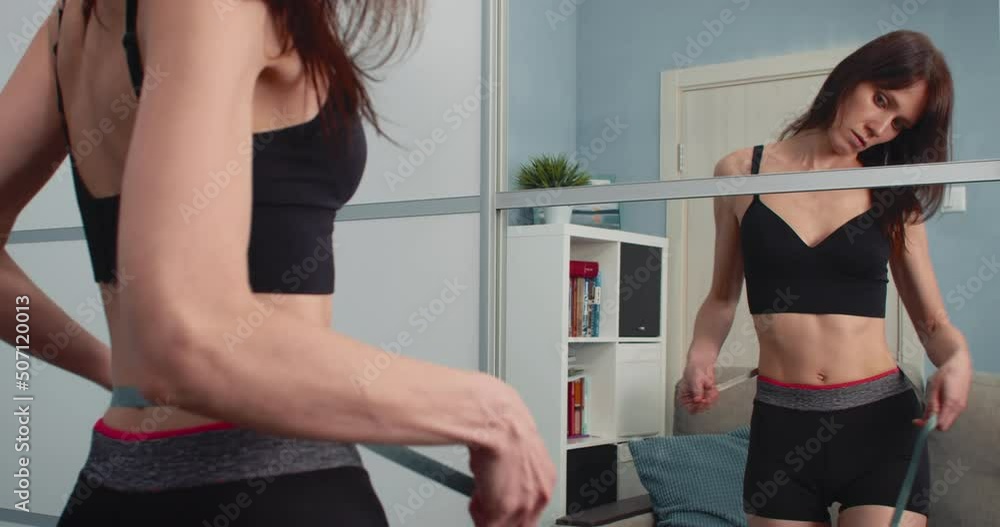 Woman with beautiful figure measures her waist with a measuring tape, after a diet and sports checks the result. Slim figure after weight lose Woman with beautiful figure measures her waist with a measuring tape, after a diet and sports checks the result. Slim figure after weight lose