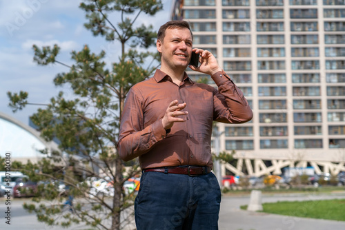 Portrait of happy man in city talking with mobile phone. Handsome man cell phone call smile outdoor city street