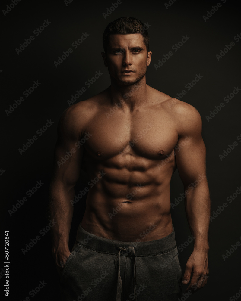 Shirtless sexy muscled male model standing in studio Shirtless sexy muscled male model standing in studio