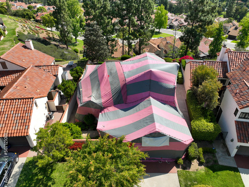 Covered villa with a red and gray tent while being fumigated for termites, San Diego, California, USA. April 17th, 2022 photo