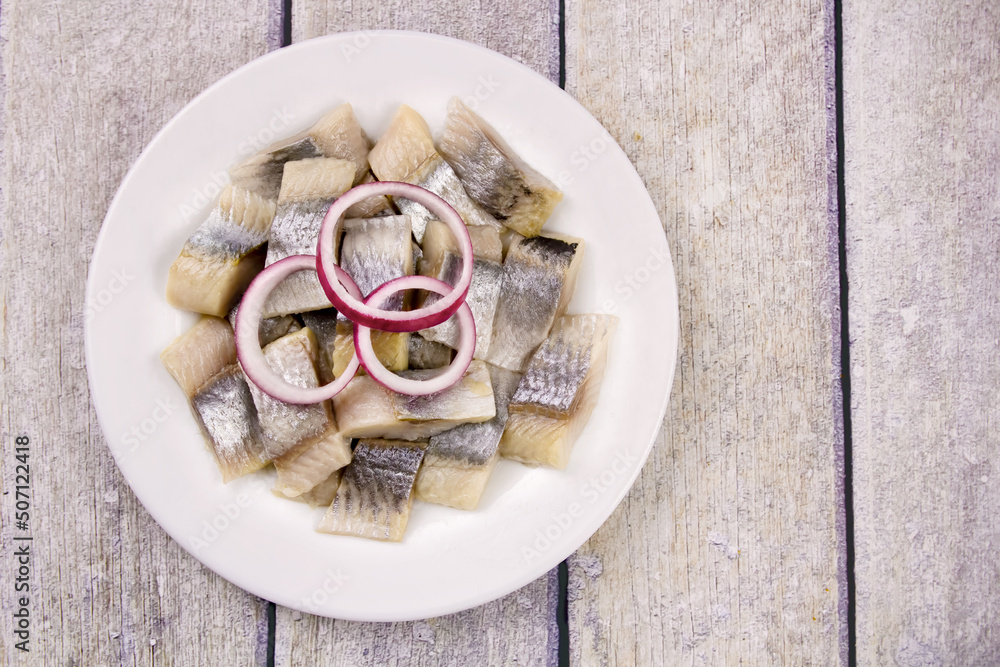 Mediterranean herring fillet served on a plate with chopped and parsley on the table