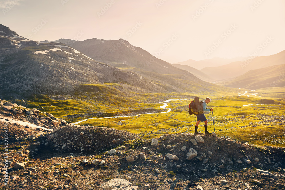 Obraz premium Hiker tourist walking at mountain valley at sunset