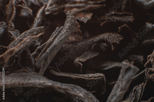 Black loose leaf tea as a background. Texture of dry black tea leaves. Dark background. Extreme macro mode. black leaf tea closeup