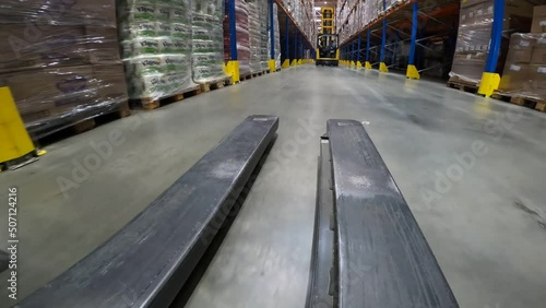 The forklift rides through the warehouse in first-person view. The forklift works in a modern warehouse. The working process. Work of special equipment in the warehouse, pov photo