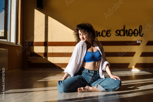 Dancer young girl in casual clothes dancing contemporary dance indoors the hall in morning sun lights