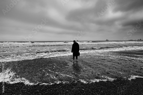 A lonely figure contemplates a gloomy stormy Sea  photo