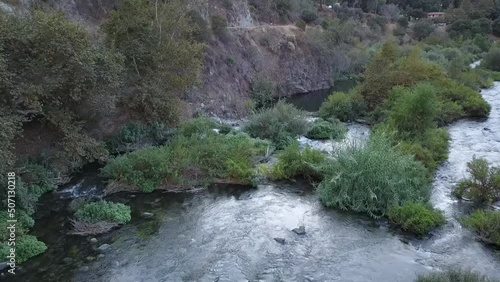 aerial footage of river water flowing over the rocks surrounded by lush green trees and plants surrounded by mountains at Azusa Wilderness Park in Azusa California USA photo