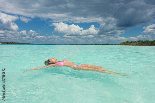 girl floating in the criystal clear of mexican caribbean photo