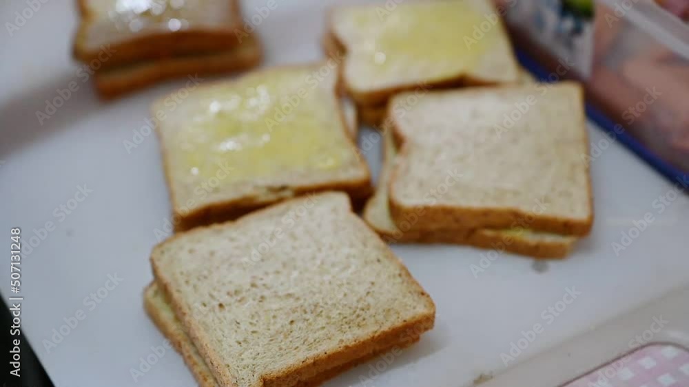 Female cook making a sandwich with butter wheat bread and tuna, sausage, crab stick Female cook making a sandwich with butter wheat bread and tuna, sausage, crab stick