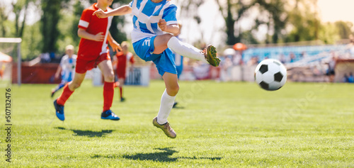 Fototapeta Naklejka Na Ścianę i Meble -  Boy Kick Soccer Ball Towards Goal and Try to Score a Goal. Kids Playing Football Ball on Grass Field. Happy School Boys Kicking Ball During Tournament Game. Children in Blue and Red Soccer Team