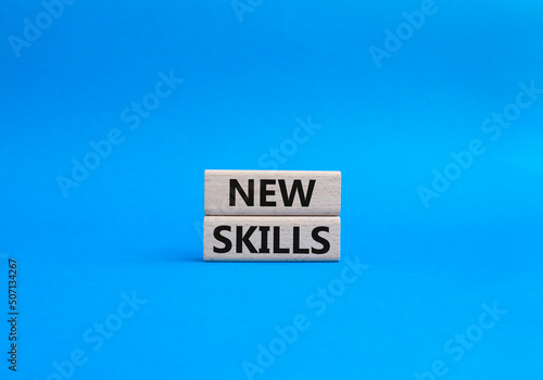 New skills symbol. Concept words 'new skills' on wooden blocks. Beautiful blue background. Business and new skills concept. Copy space.