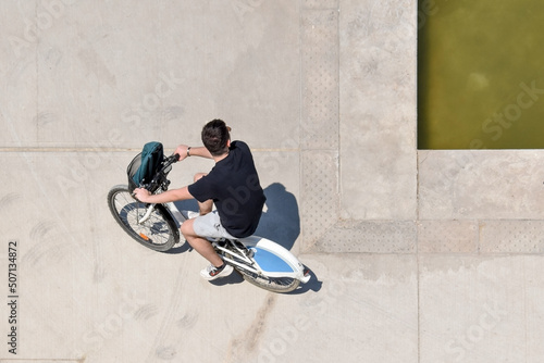 Young man riding his bike and exercising in Stavros Niarchos Cultural Center in Athens, Greece, aerial view with minimal framing and negative space on concrete background
