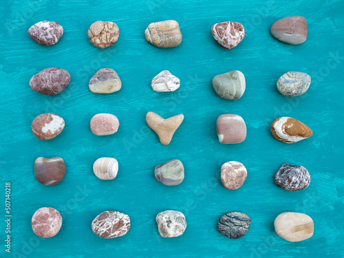 Five rows of dry sea pebbles on aquamarine background