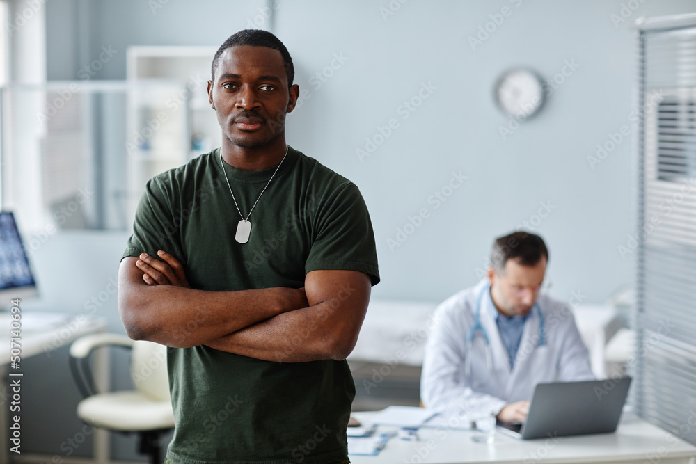 Fototapeta premium Portrait of strong young Black soldier standing with arms crossed posing on camera during medical checkup