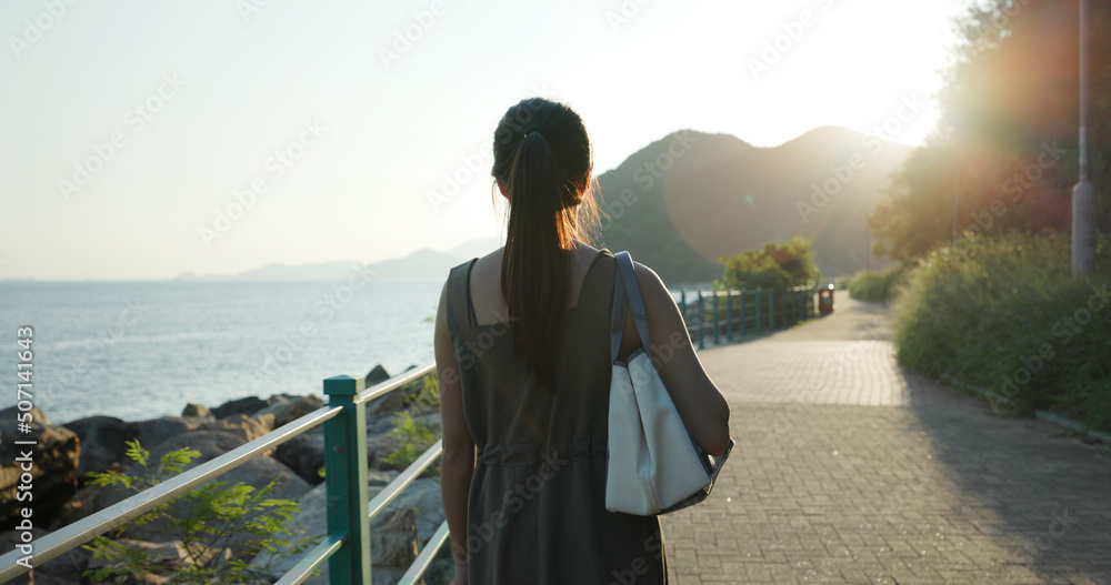 Woman walk beside the sea under sunset light
