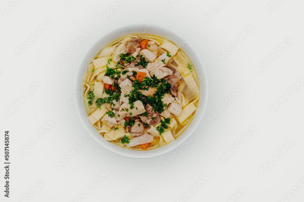 Chicken soup in a bowl with noodles, fresh vegetables and chicken meat photographed from above on a white background Chicken soup in a bowl with noodles, fresh vegetables and chicken meat photographed from above on a white background