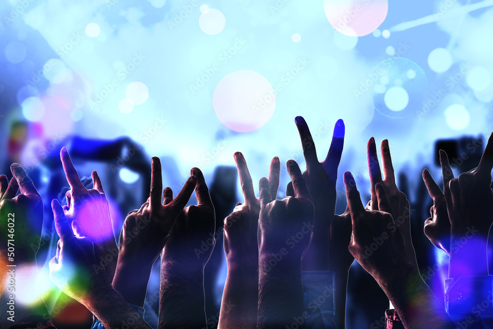 Crowd fans hand silhouettes at rock pop concert, party, event. Abstract blurred background. Many arms of people having fun