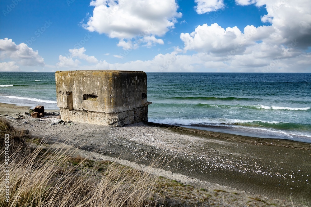 The bunker stands on the beach near the Black Sea with a war on the background of a cloudy sky