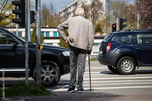 Older man waiting on the red light with cars waiting in the traffic jam