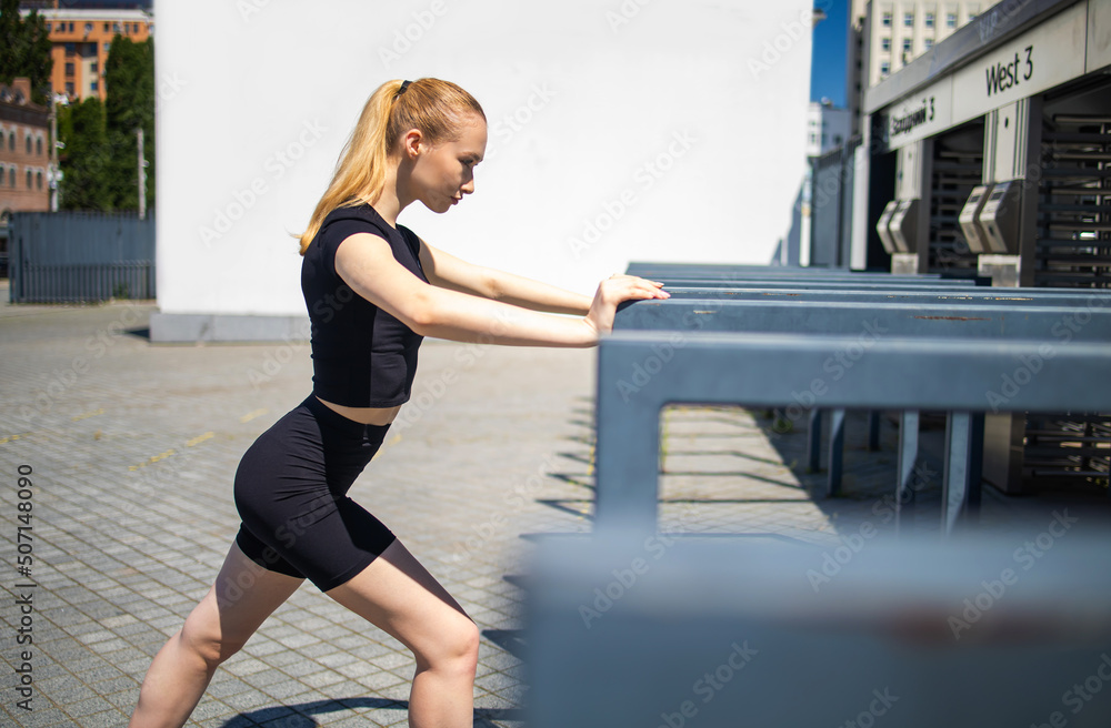 Fitness runner body close up, woman doing warm-up before jogging, stretching leg muscles, Female athlete prepares legs for cardio workout, outdoor exercise in city.