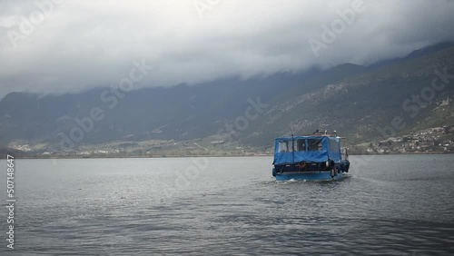 Scenic view of small boat on lake pamvotis in Ioannina, Epirus, Greece, overlooking mountains with cloudy skies photo