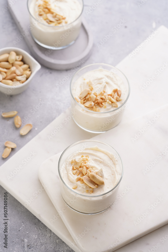 Creamy dairy yoghurt dessert with mascarpone, cream cheese and peanut butter in glasses on marble tray Creamy dairy yoghurt dessert with mascarpone, cream cheese and peanut butter in glasses on marble tray