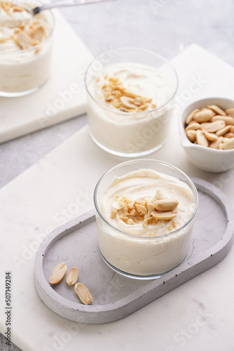 Creamy dairy yoghurt dessert with mascarpone, cream cheese and peanut butter in glasses on concrete tray